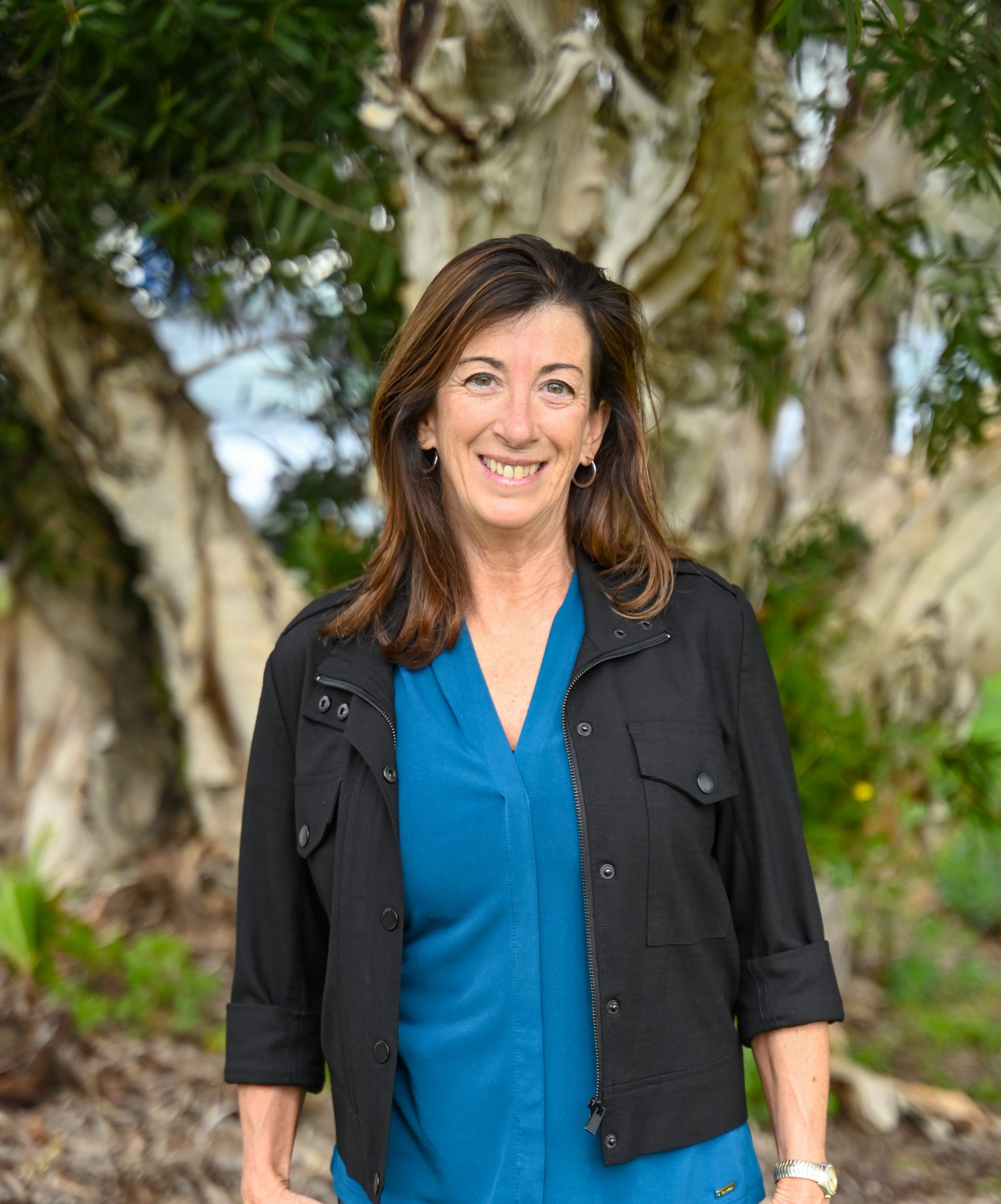 Debbi Levis smiling in front of a tree in Cardiff-by-the-Sea, California