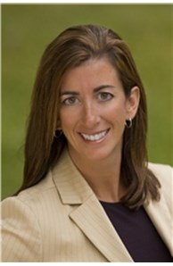 Female real estate agent in a suit with brown hair and a smile